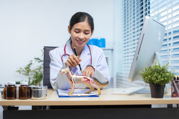 A confident Asian female veterinarian sits at her desk, providing online consultations. She uses...