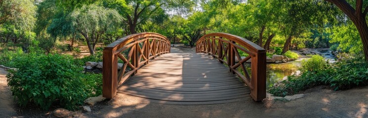 Wooden arch bridge spanning a tranquil garden stream. Lush greenery surrounds the path