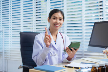 A confident Asian female veterinarian sits at her desk, calculating pet care costs using a...