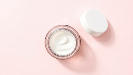 Elevated top view of a cosmetic jar with creamy white substance and a lid positioned on a soft pale pink background