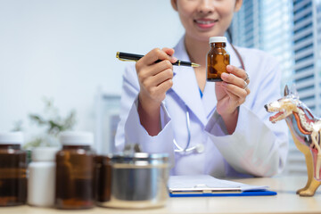 Confident Asian female veterinarian sits at her desk, preparing medications and vaccines for pets, including rabies shots and flea treatment. providing effective care in her animal clinic.