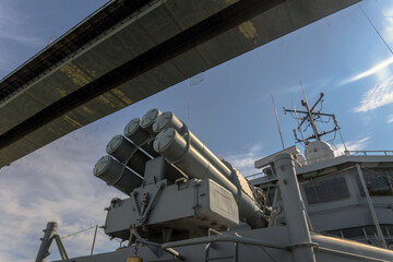 A warship passes under a bridge.
