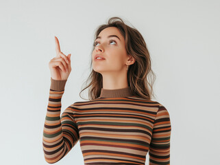 Full-Body Portrait of a Smiling Woman in Striped Top Pointing Up – Studio Shot with White Background, Perfect for Advertising, Branding, or Marketing Campaigns