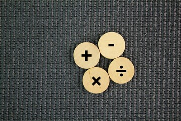 Wooden circle with plus, minus, multiplication and division symbols. Four Basic Mathematical...