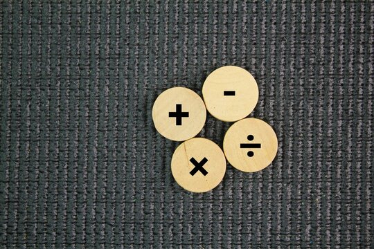 Wooden circle with plus, minus, multiplication and division symbols. Four Basic Mathematical Operations. Addition, Subtraction, multiplication, division.
