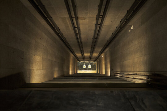 Indoor shooting range showing paper targets suspended at end of long tunnel, empty firing lane, no people present, shooting club environment