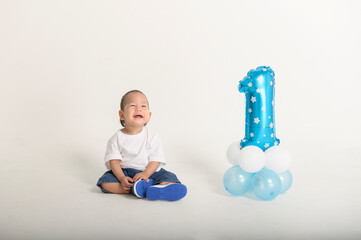 Happy First Birthday Celebration With a Cheerful Toddler and Blue Balloon Decoration