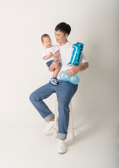 Father Holds One-Year-Old Child While Celebrating Birthday With Blue Balloon and Joyful ExpressionsFather Holds One-Year-Old Child While Celebrating Birthday With Blue Balloon and Joyful Expressions