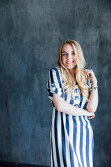 Beautiful blonde in summer striped dress laughing and rejoicing