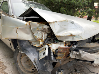 Close up of severely damaged car after front end collision. Crumpled metal, rust, and broken parts...
