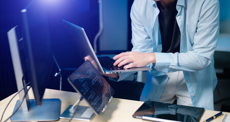 Male programmer using stylus to analyze code on tablet and monitor. Software development, coding, and tech workspace concept