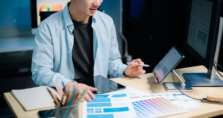 Asian male programmer working with tablet, laptop, and desktop in tech office. Coding, software...