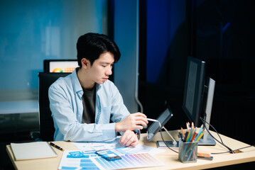 Asian UX,UI designer reviewing app wireframes and color samples in modern office. Creative process,...