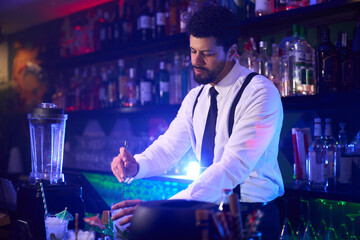 Bartender preparing cocktail in modern nightclub bar