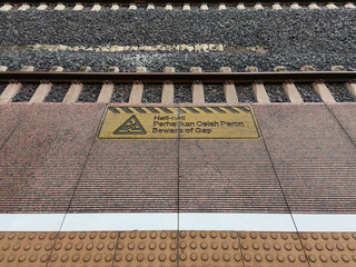 Beware of gap sign on railway station platform with tactile tiles