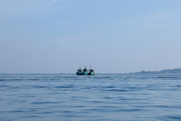 Three fishing boats at sea under a calm blue sky