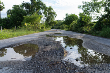 Potholed Rural Road with Water Reflections