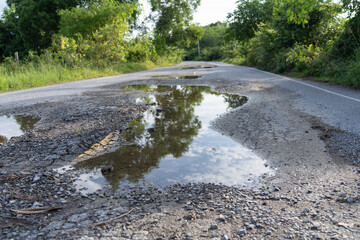 Potholed Rural Road with Water Reflections