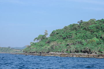 Naklejka premium Lush green tropical island coastline with blue ocean