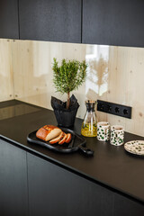 A cozy kitchen corner with fresh bread on a wooden board, herb plants, a tea carafe, and dotted ceramic cups, creating a warm and homely atmosphere