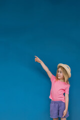 Young girl in vibrant outfit enjoys playful moment against blue wall