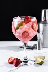 Strawberry gin tonic cocktail on white marble and black background
