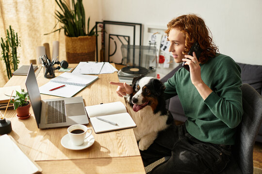Young man enjoying a cozy day at home while working on his laptop and talking on the phone