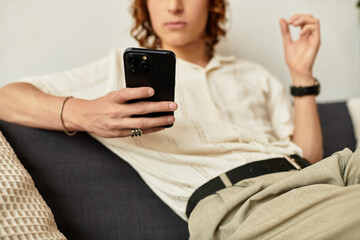 Young man relaxing at home while using a smartphone in a cozy living space