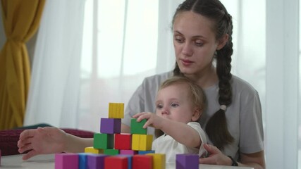 Mother and toddler play at home. Toddler explores colorful blocks. Playtime bonding with mother. Happy baby enjoying play. Mother guides toddler play. Toddler curiosity in playtime at home. - Powered by Adobe