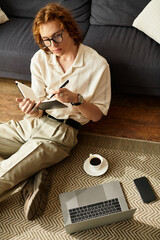 Young man enjoying a cozy afternoon at home while writing notes and sipping coffee