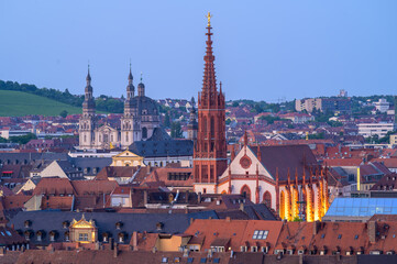 Wurzburg's Marian Chapel illuminated at dusk with city rooftops in the foreground - Germany