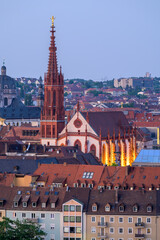 Wurzburg's Marian Chapel illuminated at dusk with city rooftops in the foreground - Germany