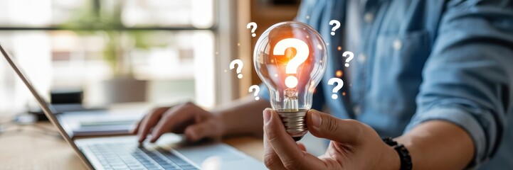 Person holding a lightbulb with question marks, symbolizing ideas.