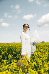 Woman in white outfit enjoying a sunny day in a field of yellow flowers