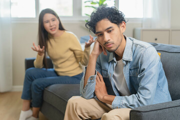 Obraz premium Family problem concept. Tension in relationship between married couple, husband and wife staying sitting separate after quarrel in the living room.