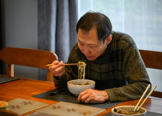 Man eating noodles with chopsticks. Home-made Chinese northern noodles with gravy (Da Lu Mian).