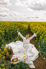 Woman enjoying a sunny day in a yellow flower field with lemons and picnic setup
