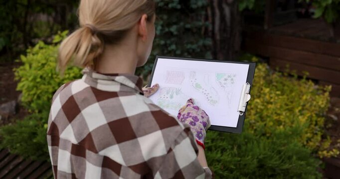 landscape design. woman gardener looking at home backyard garden plan