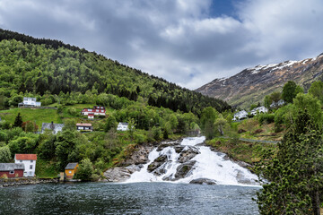 Scenic Mountain Village with Waterfall and Lush Green Foliage
