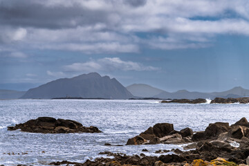 Scenic Coastal View with Mountains and Rocks Under Dramatic Cloudy Sky, Runde, Norway