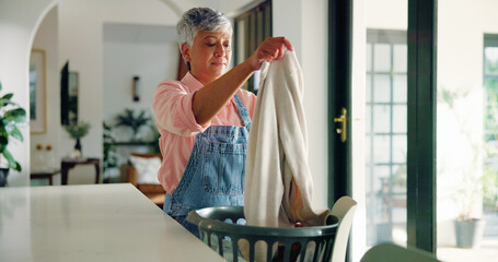 Senior woman, cleaning and folding laundry in home for housekeeping or hygiene maintenance. Daily housework, person and fabric in basket for chores, morning routine or organizing cotton in retirement
