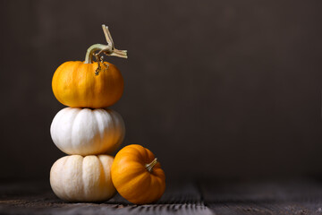 Baby Boo pumpkins arranged on wooden surface in close-up autumn scene with dark tones....