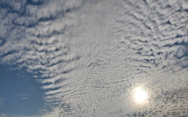 This sky photo features a unique and dramatic altocumulus cloud pattern, with dim sunlight filtering through the cloud layers. Suitable for weather themes, nature scenes, sky backgrounds, 