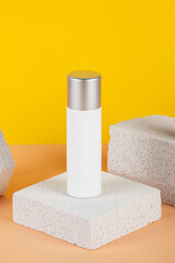 Plastic white tube for cream or lotion. Skin care or sunscreen cosmetic with stylish props on yellow background.
