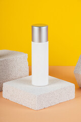 Plastic white tube for cream or lotion. Skin care or sunscreen cosmetic with stylish props on yellow background.