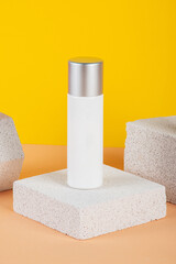 Plastic white tube for cream or lotion. Skin care or sunscreen cosmetic with stylish props on yellow background.