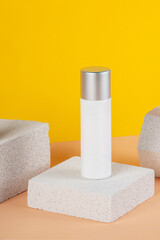 Plastic white tube for cream or lotion. Skin care or sunscreen cosmetic with stylish props on yellow background.
