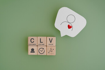 CLV for customer lifetime value, text on wooden cube blocks with people and red heart icon on real white speech bubble paper cut, green background