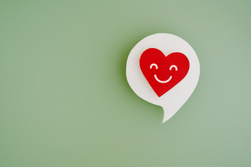 smiling red heart inside real white speech bubble paper cut on green background including copy space, for mental health, service mind, psychology consultant, core value concept