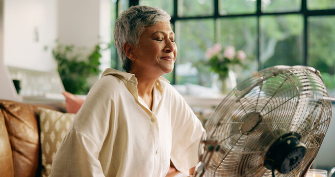 Elderly woman, hot and fan at house for heatwave, air conditioning and menopause symptoms. Senior person, relax and electric appliance for cool breeze, warm weather and relief from hormonal condition